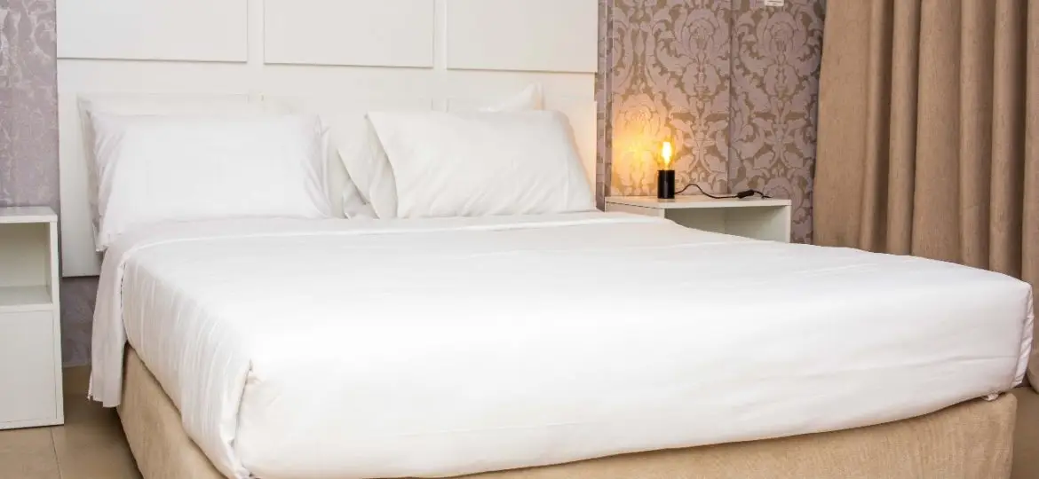 Close up photo of bedroom at Doritis Guest House, a boutique hotel, featuring a comfortable bed with a white frame.